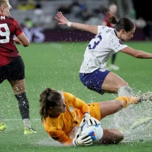 Поле, затопленное водой, вызывает споры, поскольку женская сборная США побеждает Канаду в серии пенальти и выходит в финал Кубка золотой лиги.